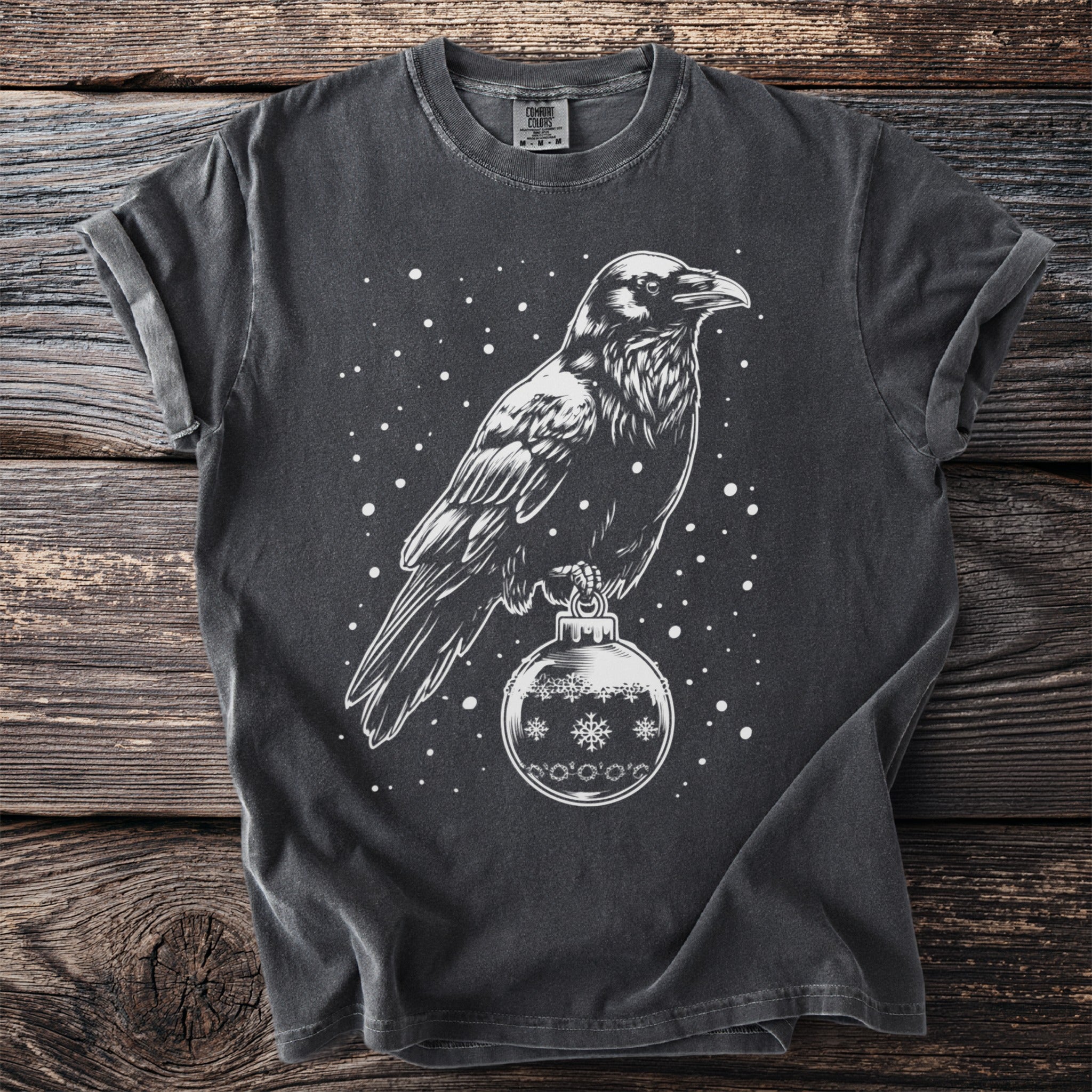 Dark t-shirt with white crow perched on a snowflake ornament design.