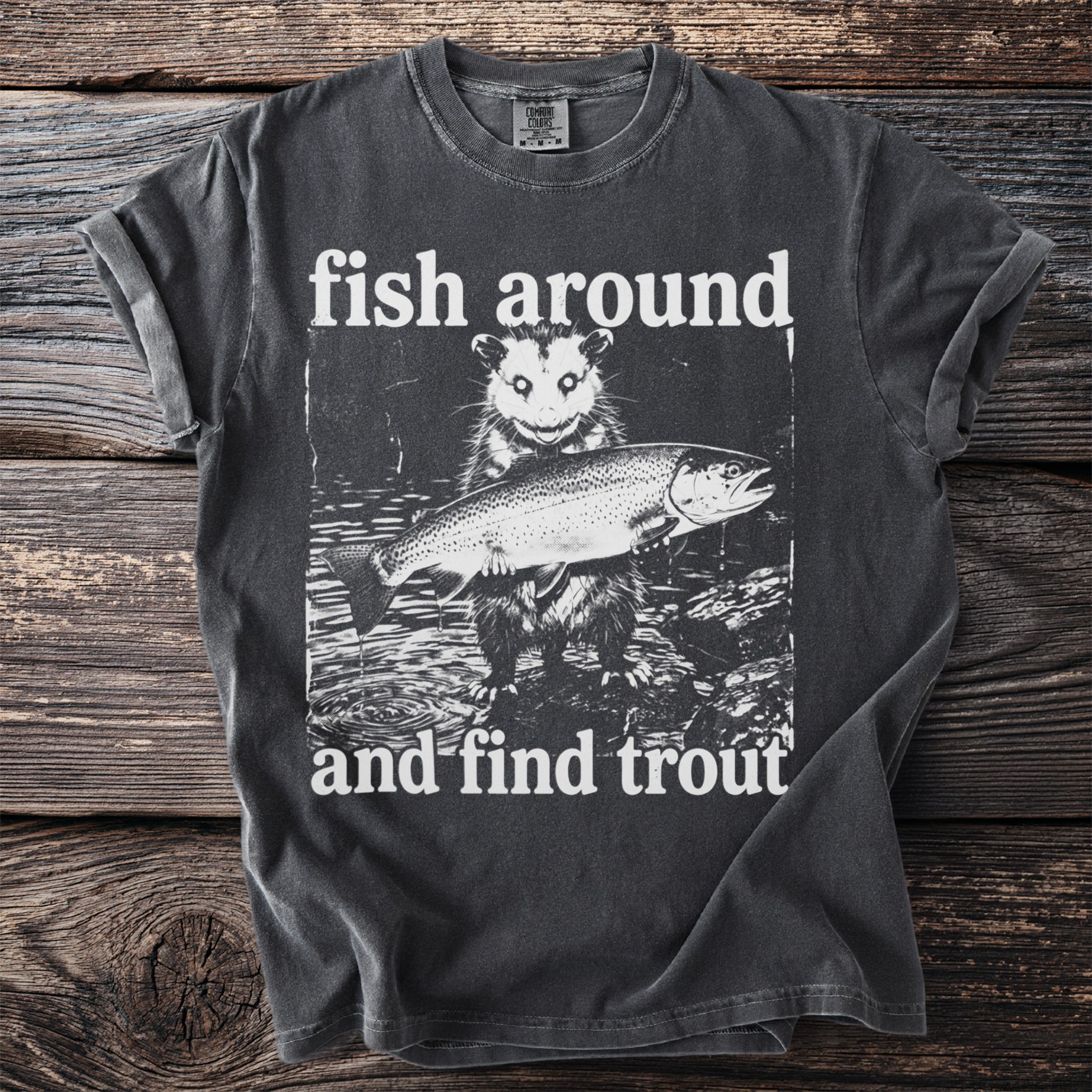 T-shirt graphic featuring an opossum holding a trout with text "fish around and find trout".