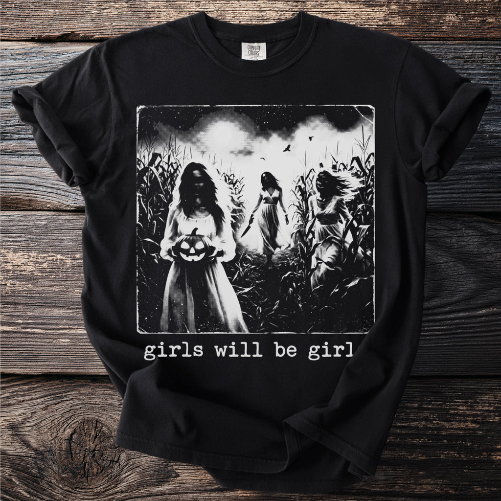 T-shirt graphic shows three ghostly figures in a cornfield with text "girls will be girl".