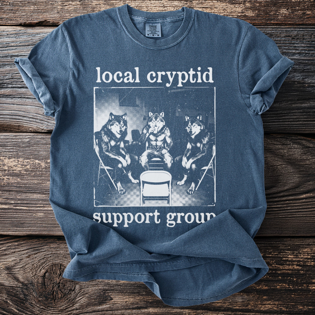 Blue t-shirt with "local cryptid support group" text and three wolves.