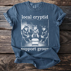 Blue t-shirt with "local cryptid support group" text and three wolves.