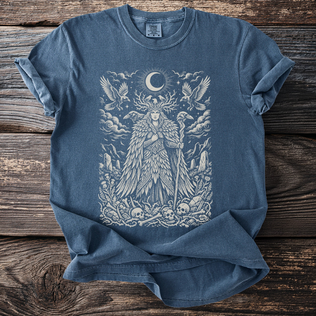 Blue t-shirt with a white illustration of a woman with antlers, birds, moon, and skulls.
