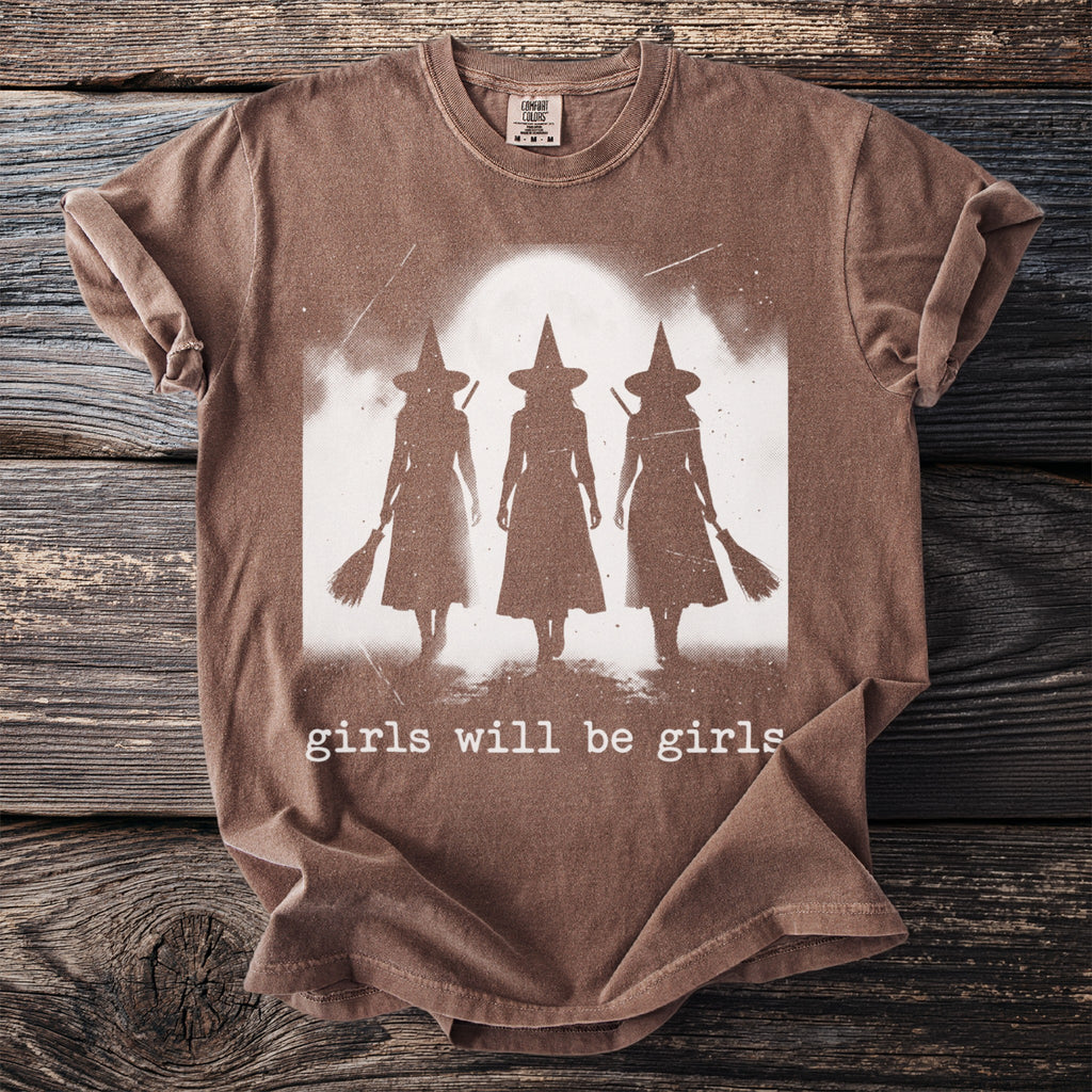 Brown t-shirt with graphic of three witches and the text "girls will be girls".