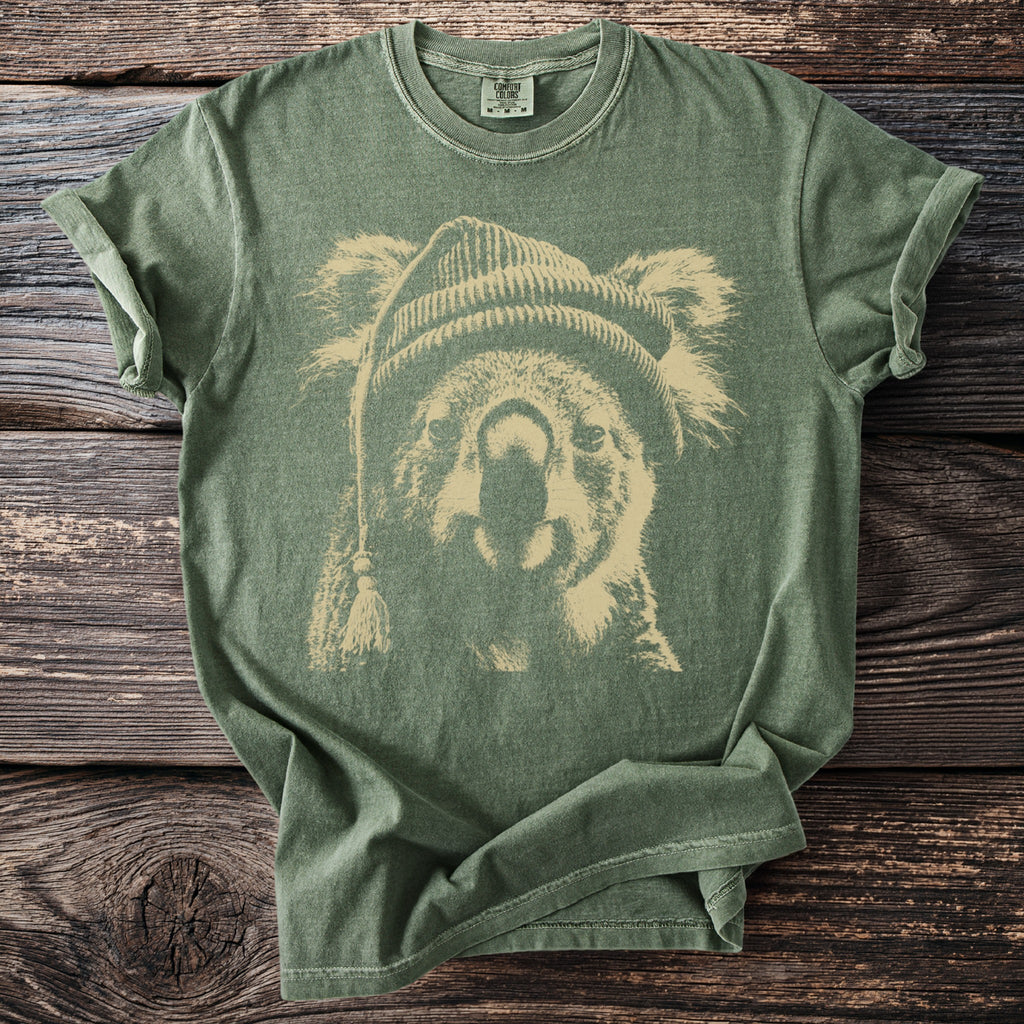Green t-shirt with a beige distressed print of a koala wearing a beanie.