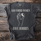 Dark grey t-shirt with text "GOD FORBID WOMEN HAVE HOBBIES" and celestial graphic.