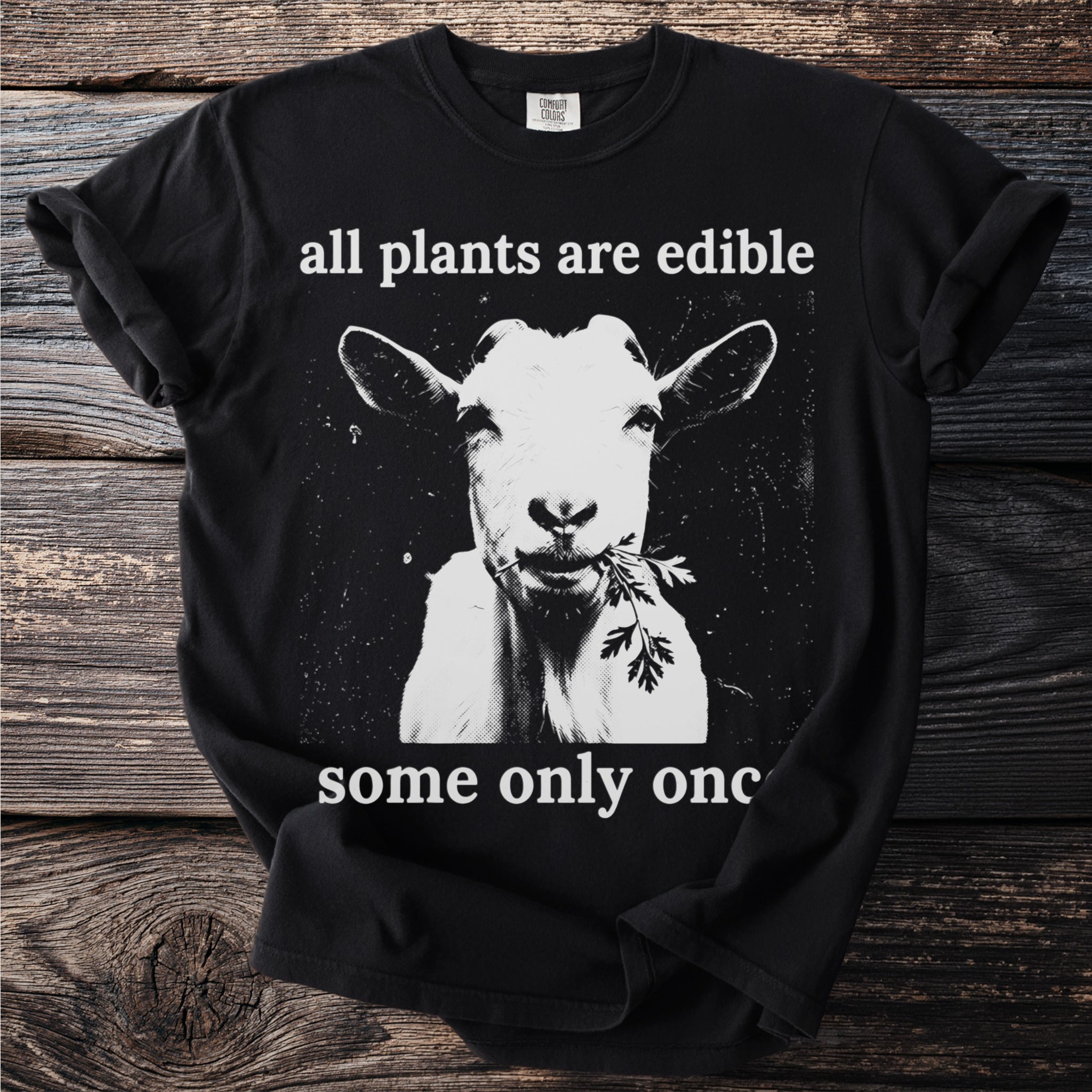 Black t-shirt with a goat eating a sprig and text "all plants are edible some only once".