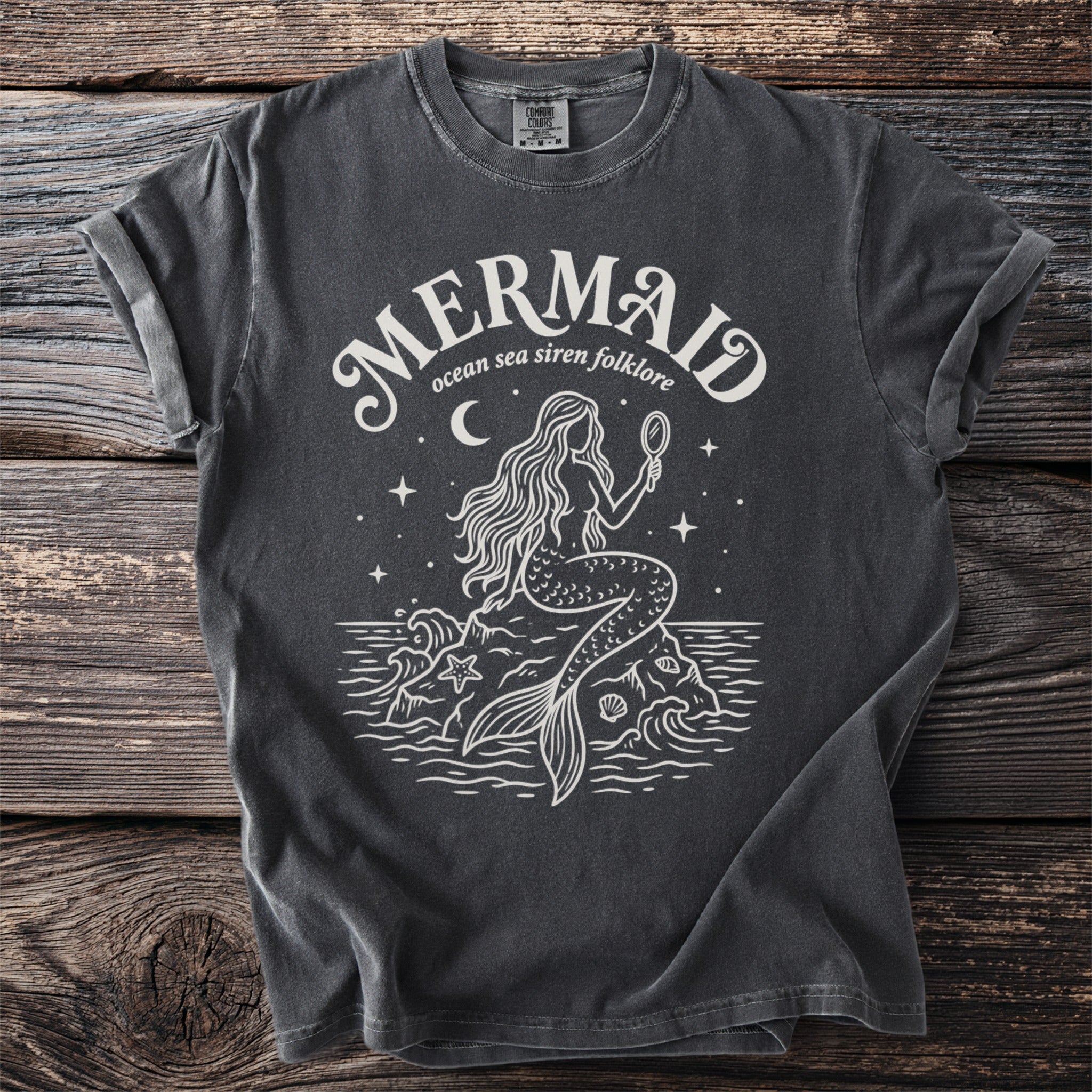 Dark grey t-shirt with white graphic of a mermaid holding a mirror, "MERMAID ocean sea siren folklore" text.