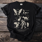 Black t-shirt featuring "The Cryptid Field Guide" with illustrations of Mothman, Nessie, Jackalope, Jersey Devil, Chupacabra, and Sasquatch.