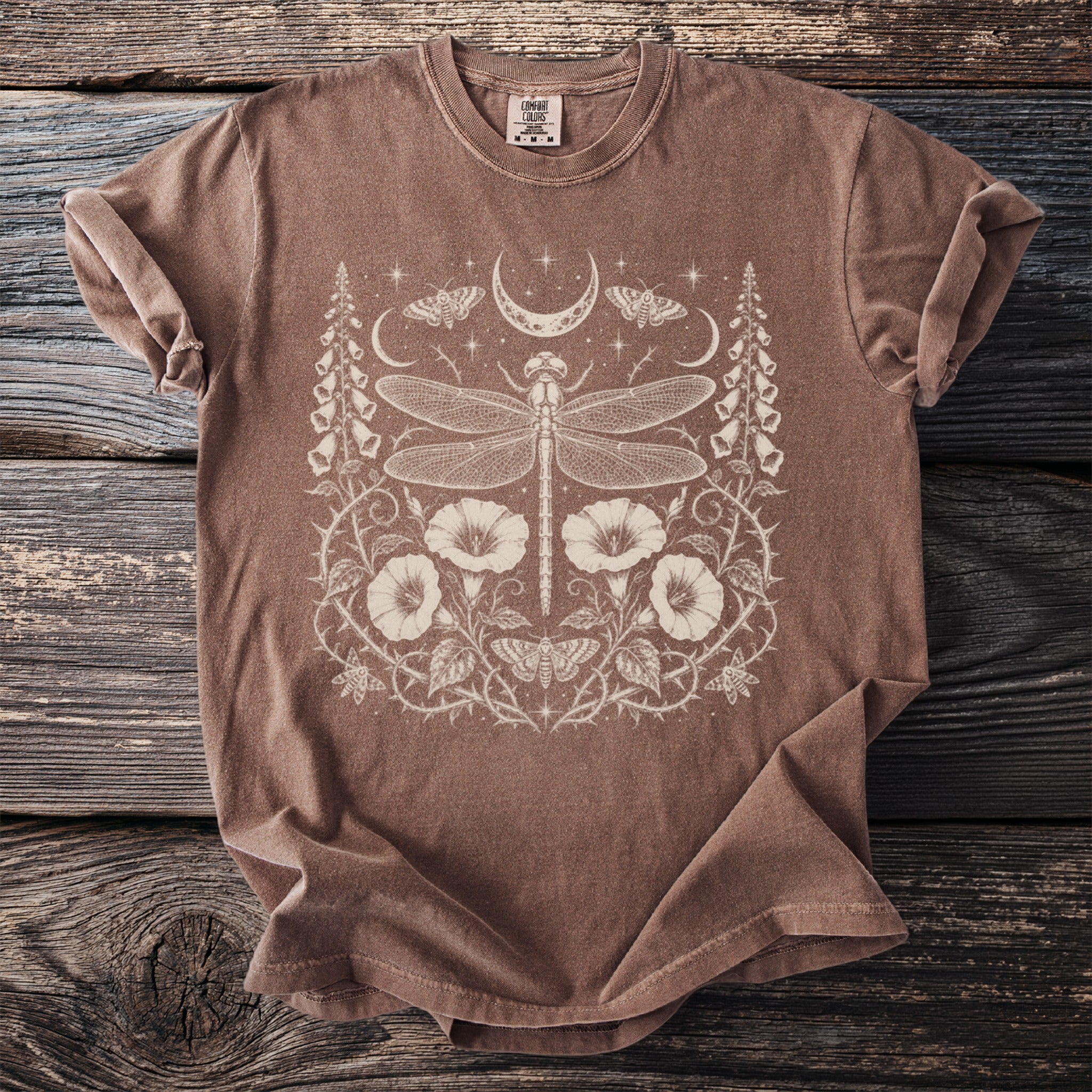Brown t-shirt with a cream dragonfly, moon, moth, and floral design.