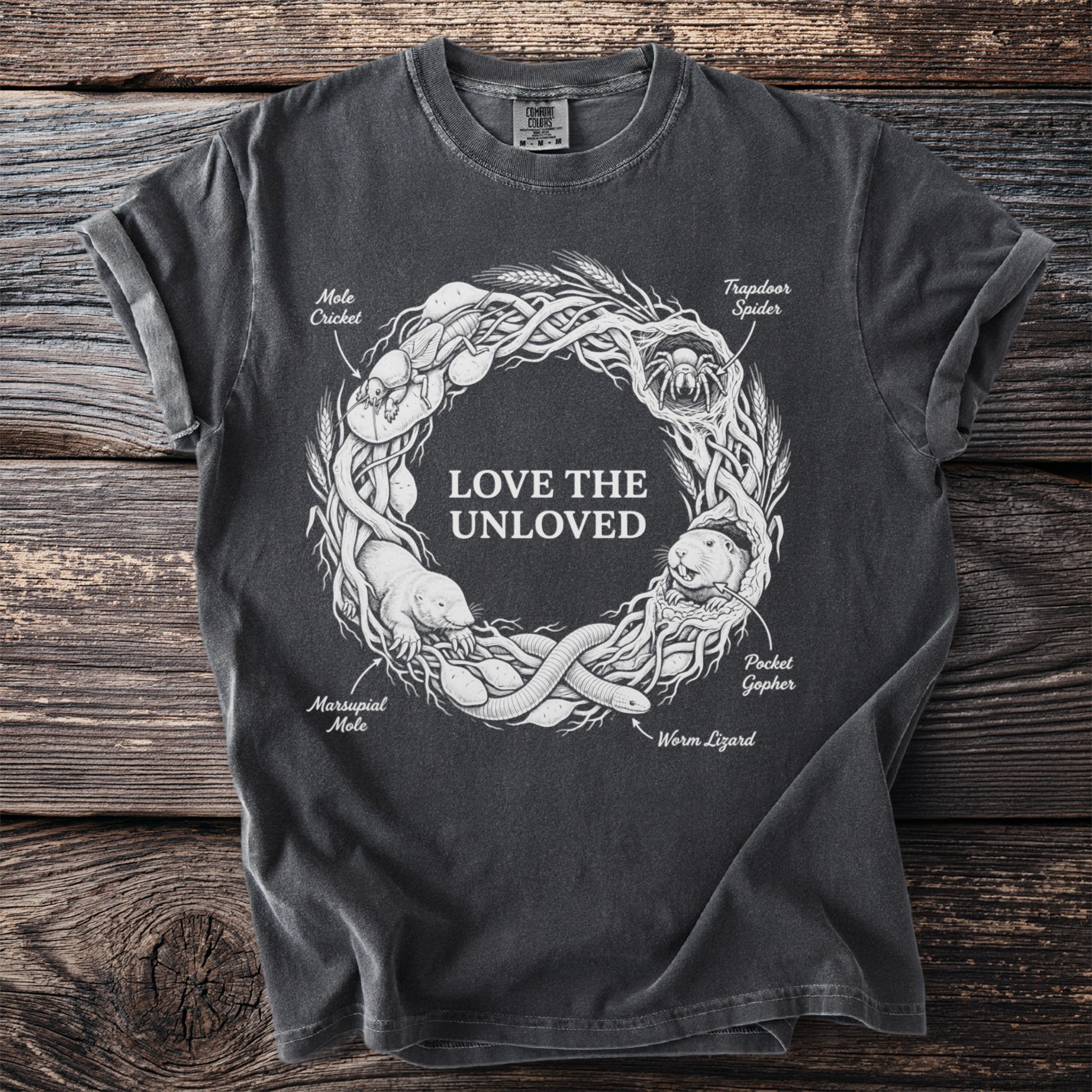 Dark t-shirt with "Love the Unloved" text and wreath of creatures.