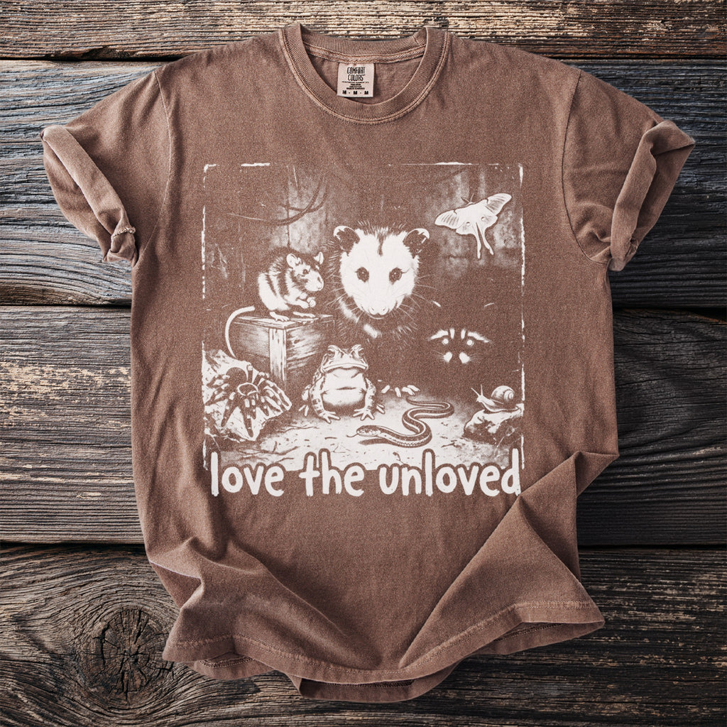 Brown t-shirt with illustration of possum, rat, frog, spider, snake, snail, moth, and text "love the unloved".
