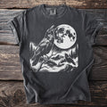 T-shirt with a black and white graphic of two ravens, a full moon, and a mountain landscape.