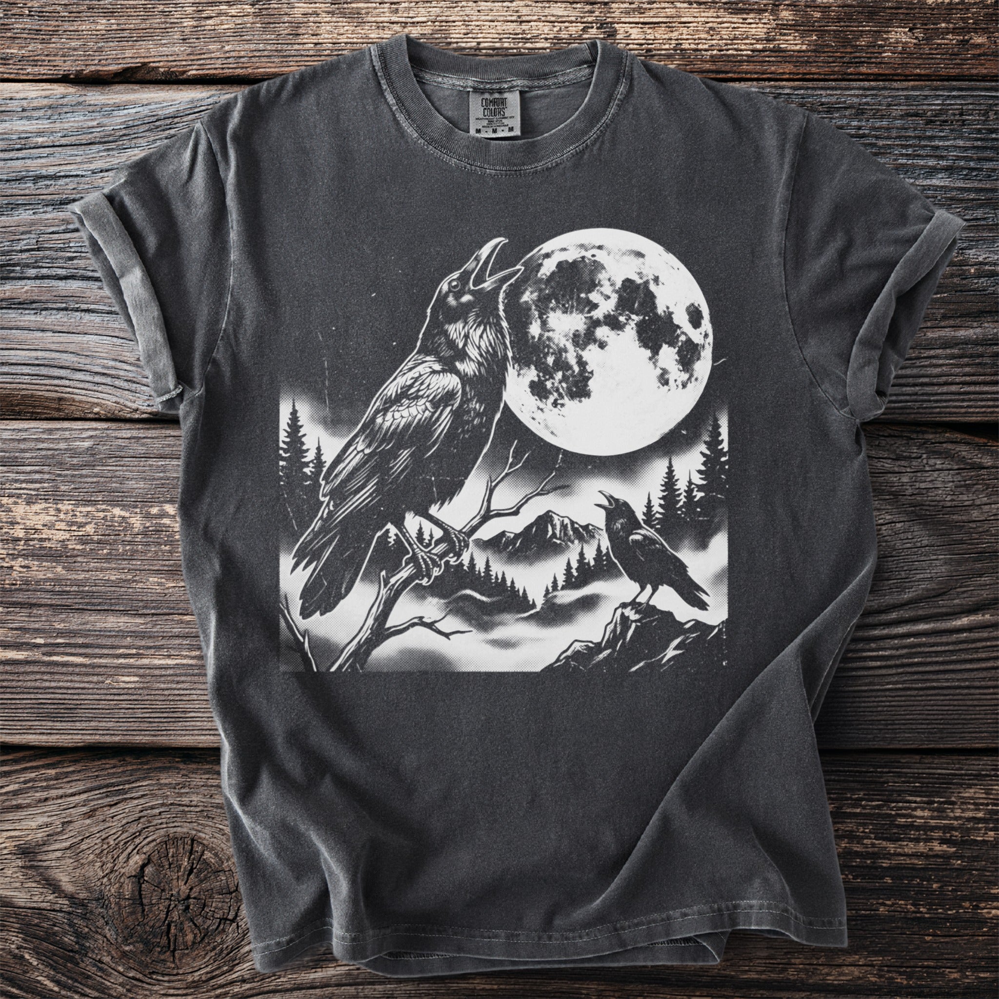 T-shirt with a black and white graphic of two ravens, a full moon, and a mountain landscape.