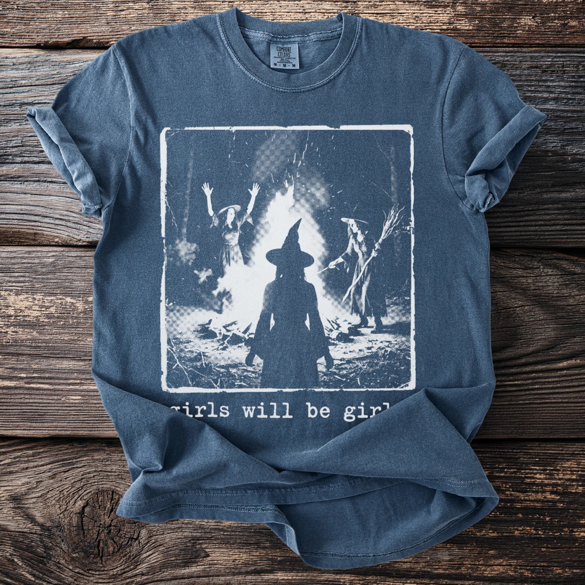 T-shirt with witches around a bonfire and "girls will be girls" text.
