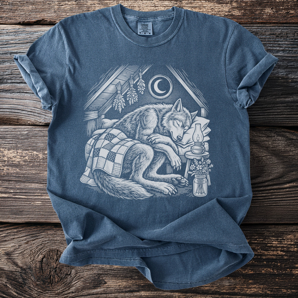 T-shirt with white linocut-style illustration of a sleeping wolf under a crescent moon.