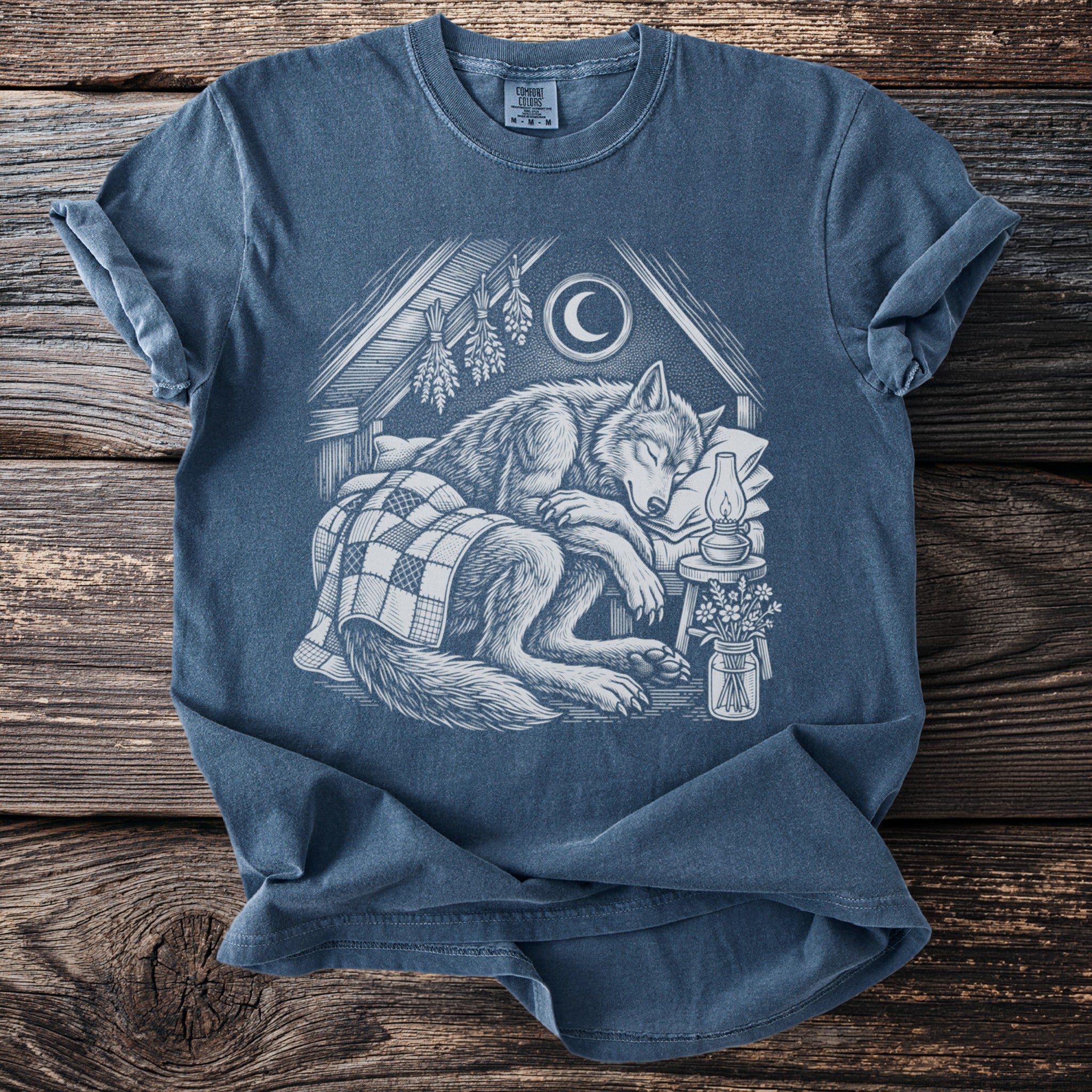 T-shirt with white linocut-style illustration of a sleeping wolf under a crescent moon.