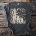 T-shirt with a linocut-style print of a raven on logs among birch trees.