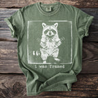 Green t-shirt with distressed graphic of a raccoon inside a frame and text "i was framed".