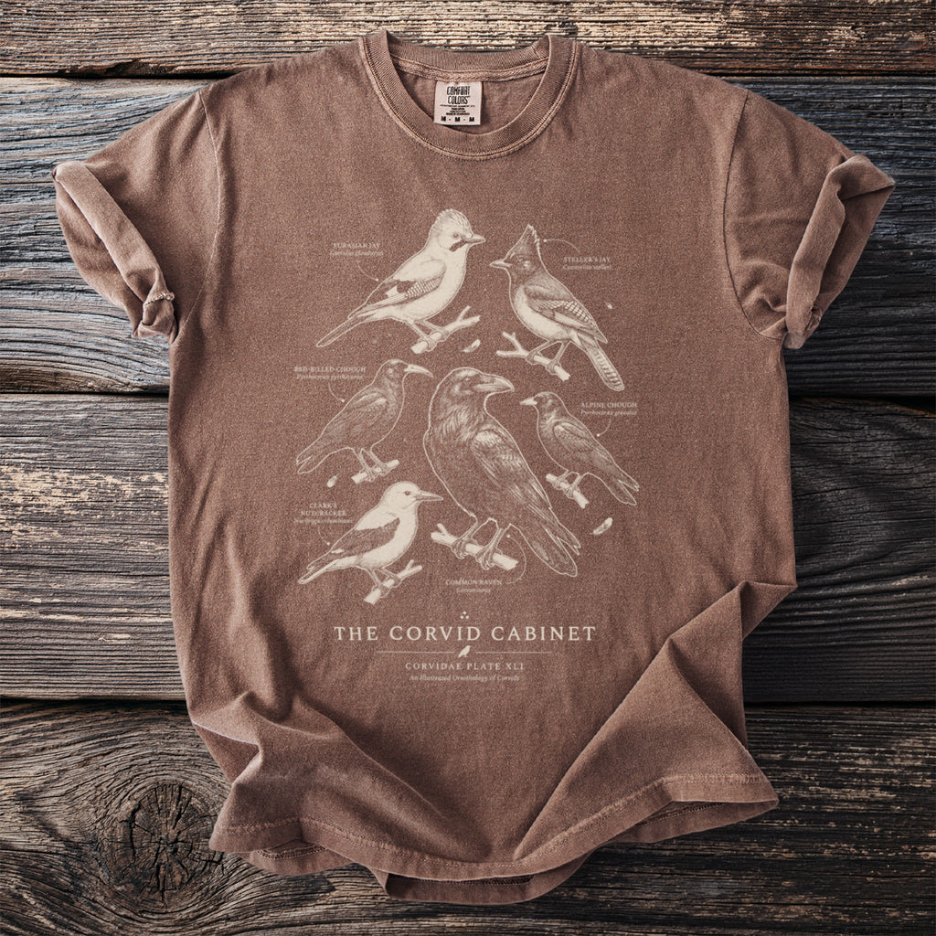 Brown t-shirt with a vintage illustration of various corvid birds and text.