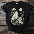 Black t-shirt with a nocturnal moth and floral illustration under a moonlit sky.