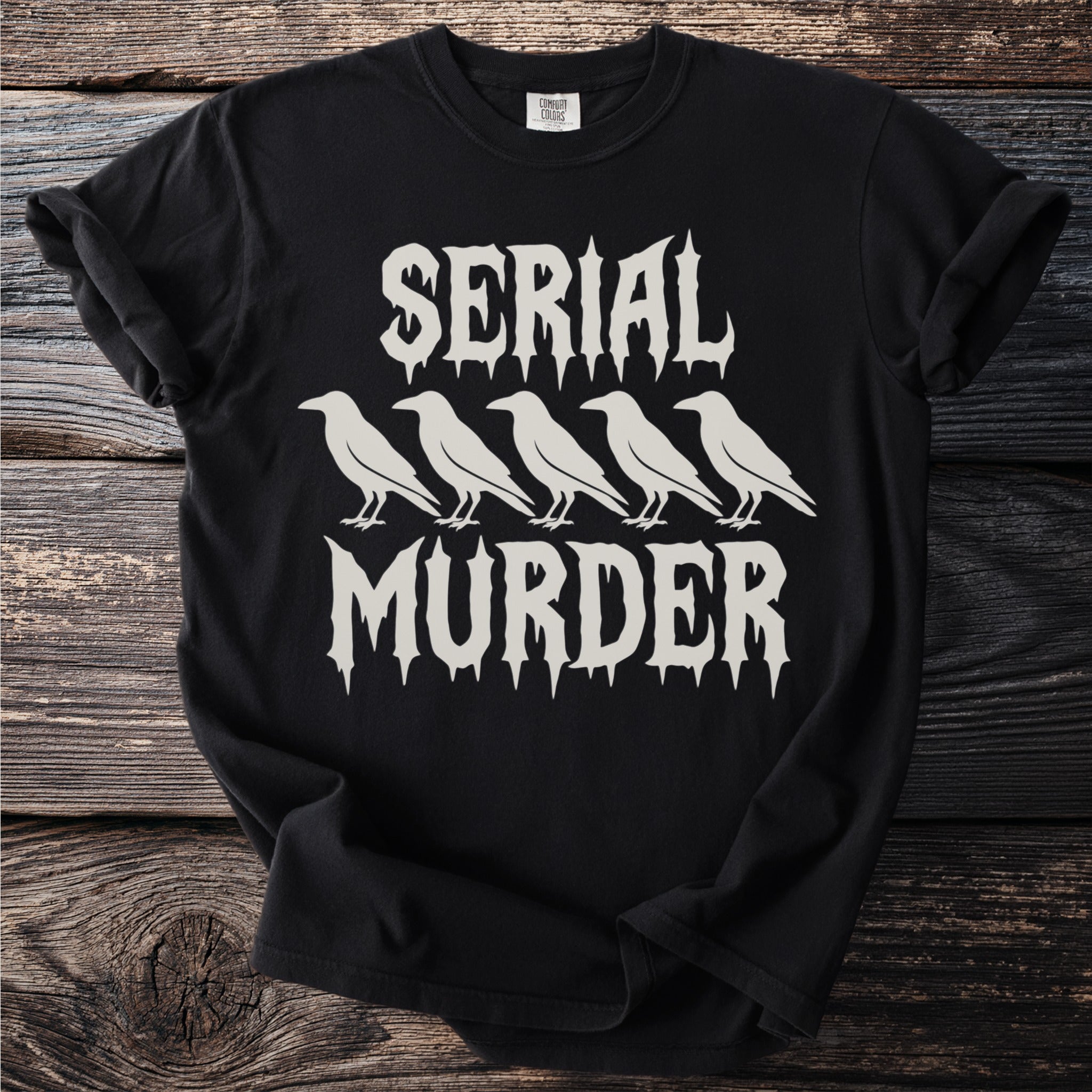 Black t-shirt with white text "SERIAL MURDER" and five crow silhouettes.