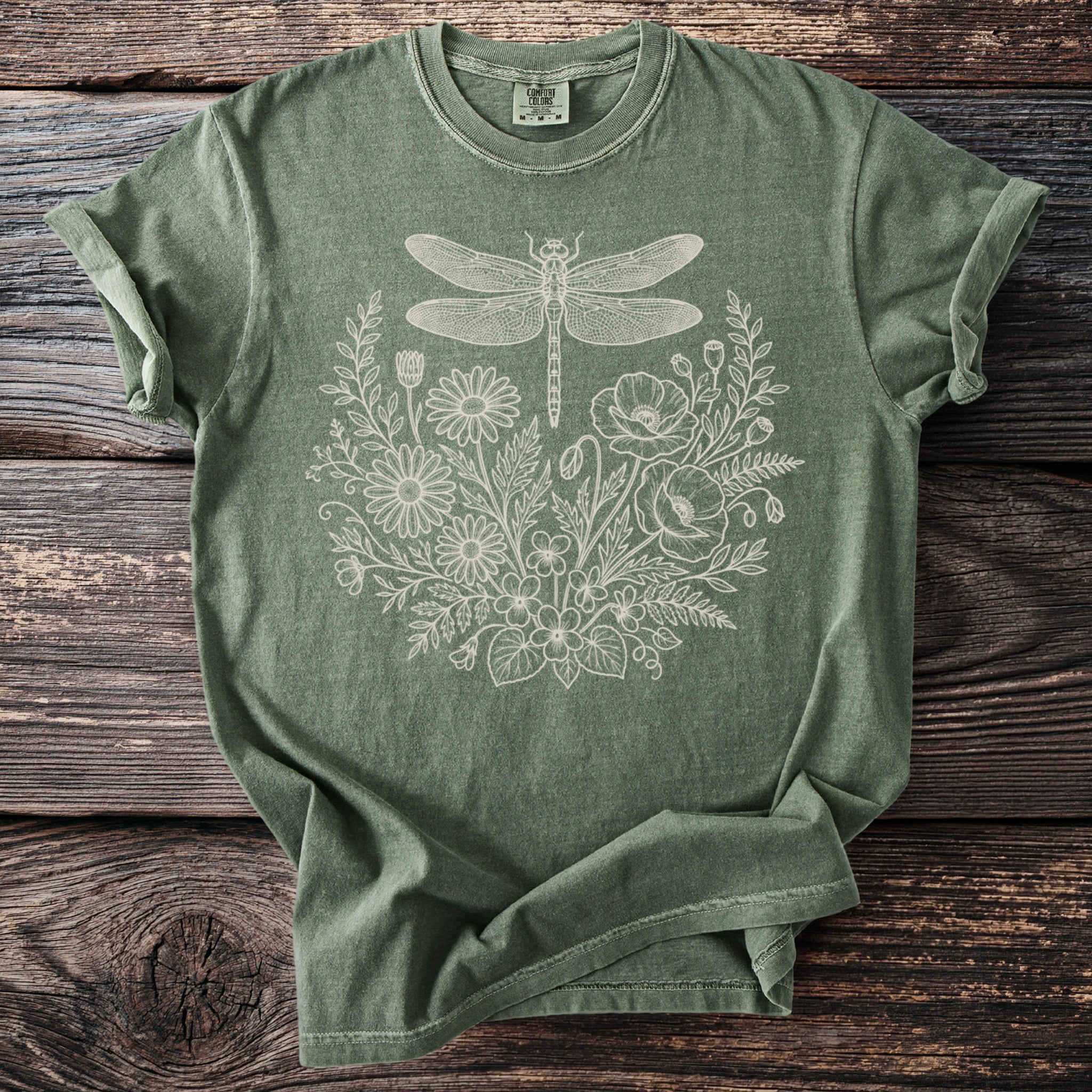 Green t-shirt with a detailed line drawing of a dragonfly and floral arrangement.