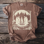 Brown t-shirt with a graphic of four cloaked figures around a campfire in a forest.