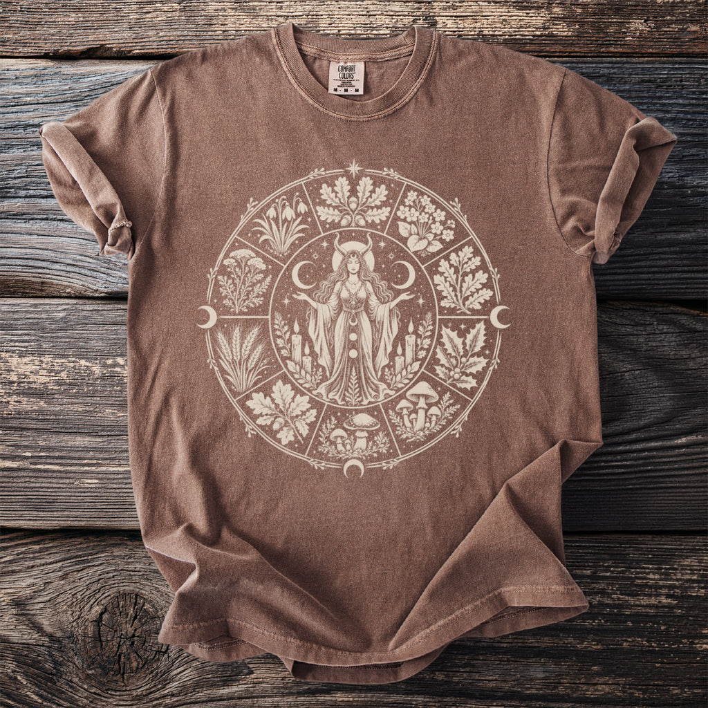 Brown t-shirt with a circular graphic featuring a woman, plants, mushrooms, candles, and moons.