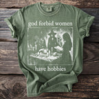 Green t-shirt with "god forbid women have hobbies" text and a witch illustration.