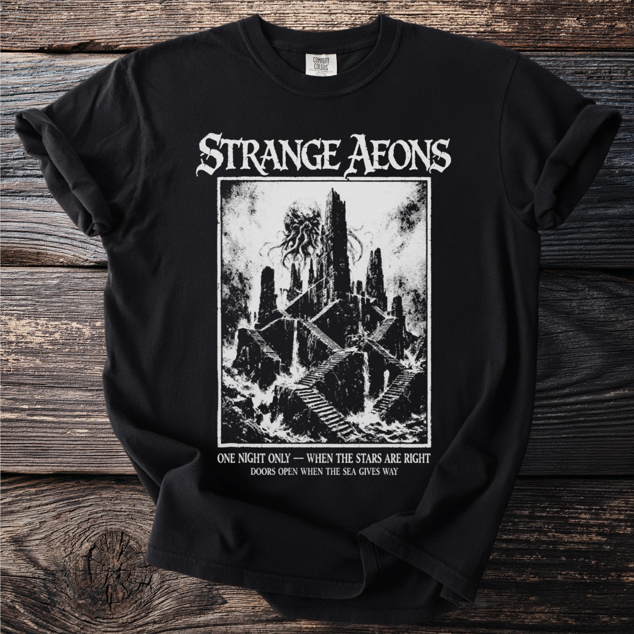 Black t-shirt with "Strange Aeons" text and a dark, gothic castle illustration.