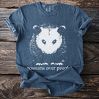 Blue t-shirt with white possum graphic and text "possums over peopl".