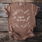 Brown t-shirt with white dragonfly and floral design reading "respect the locals".