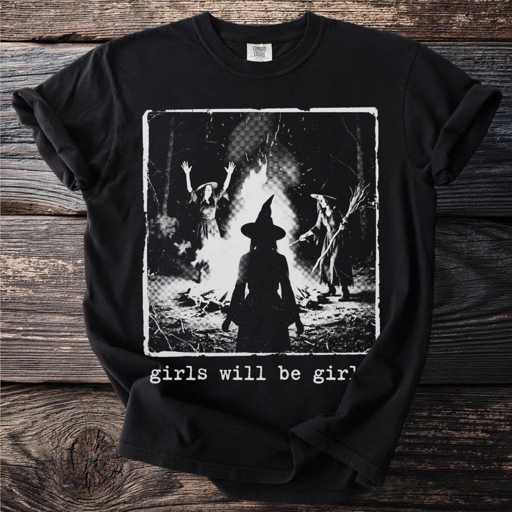 Black t-shirt with a graphic of three witches around a bonfire, text reads "girls will be girl".