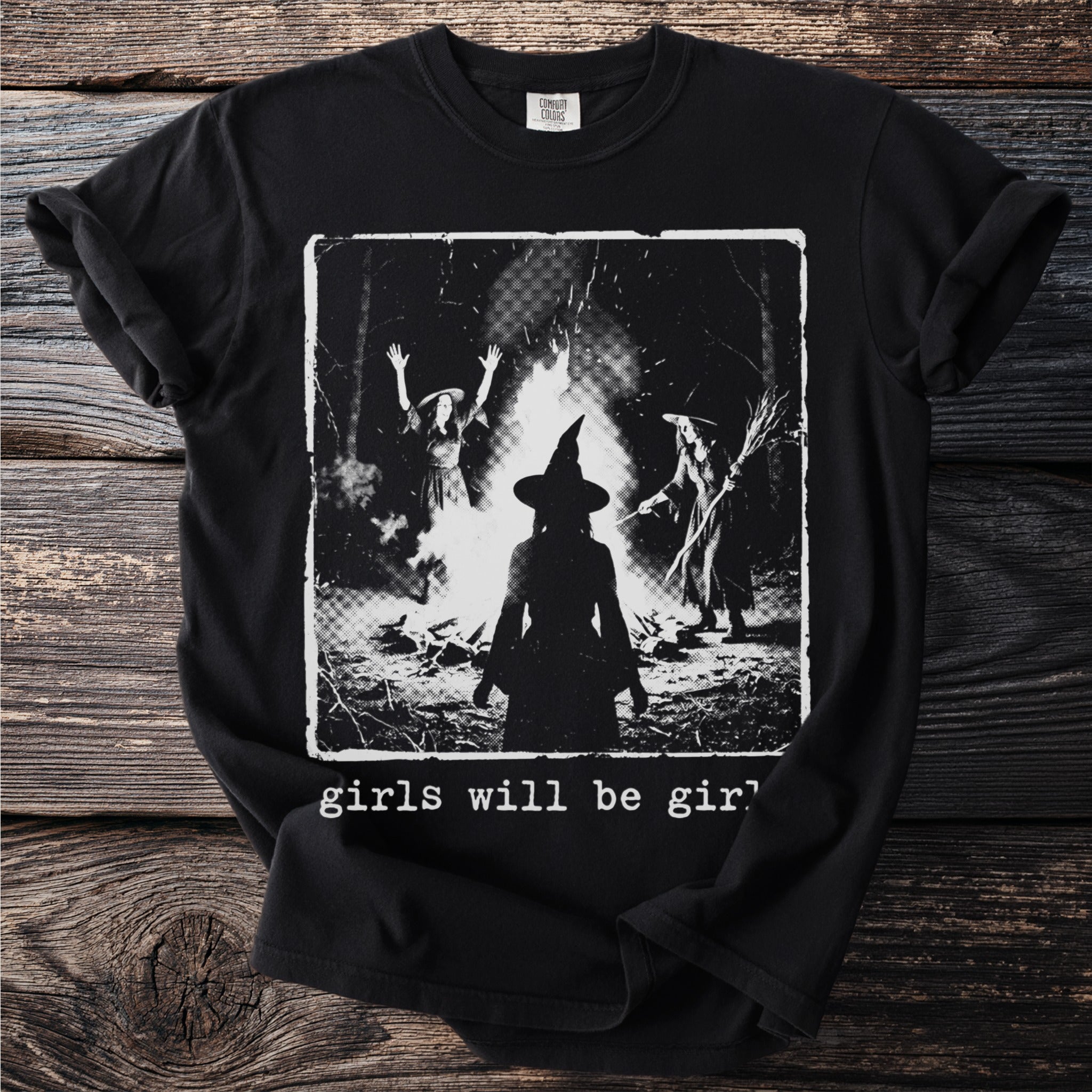 Black t-shirt with a graphic of three witches around a bonfire, text reads "girls will be girl".