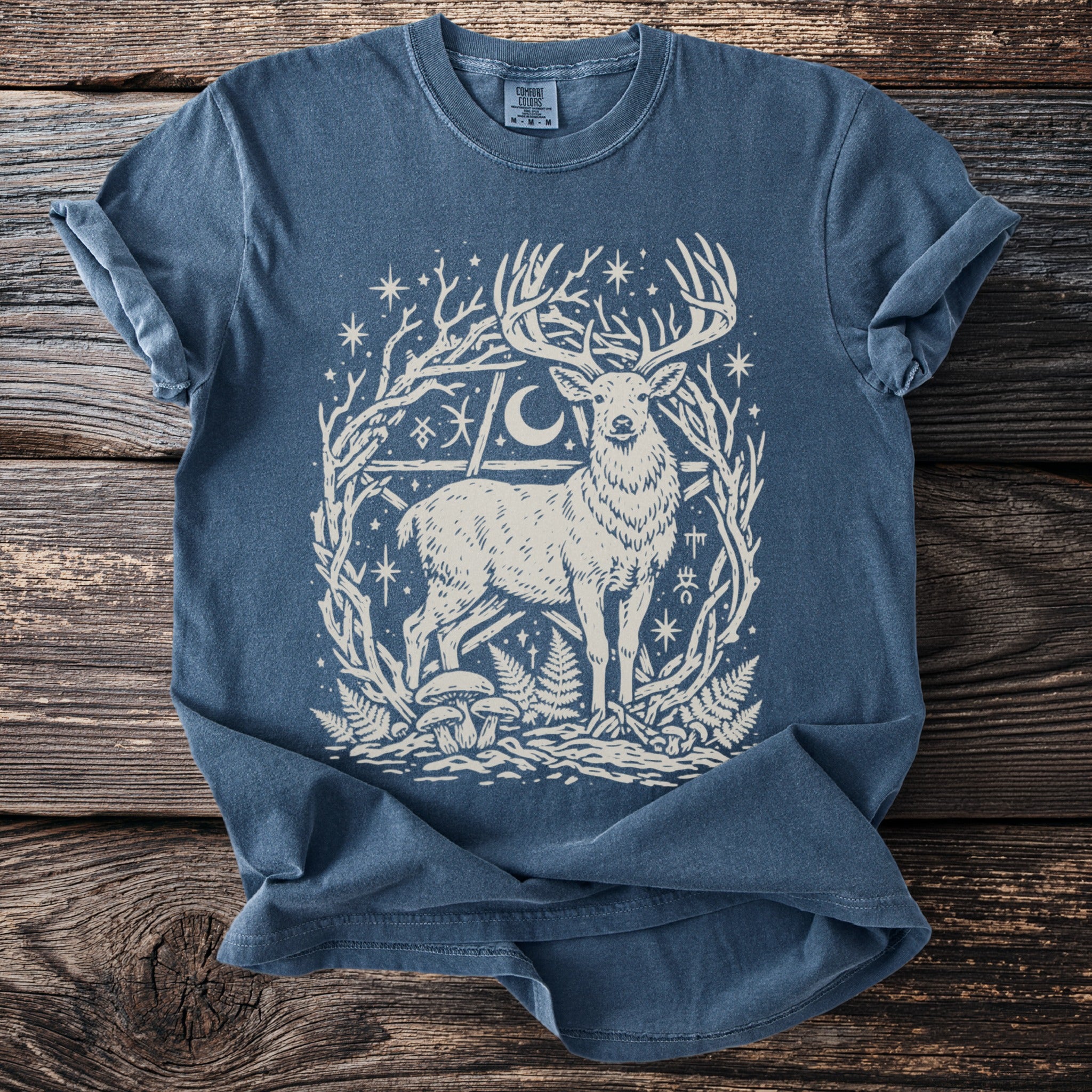Blue t-shirt with a fawn, moon, stars, and nature symbols within a pentagram.