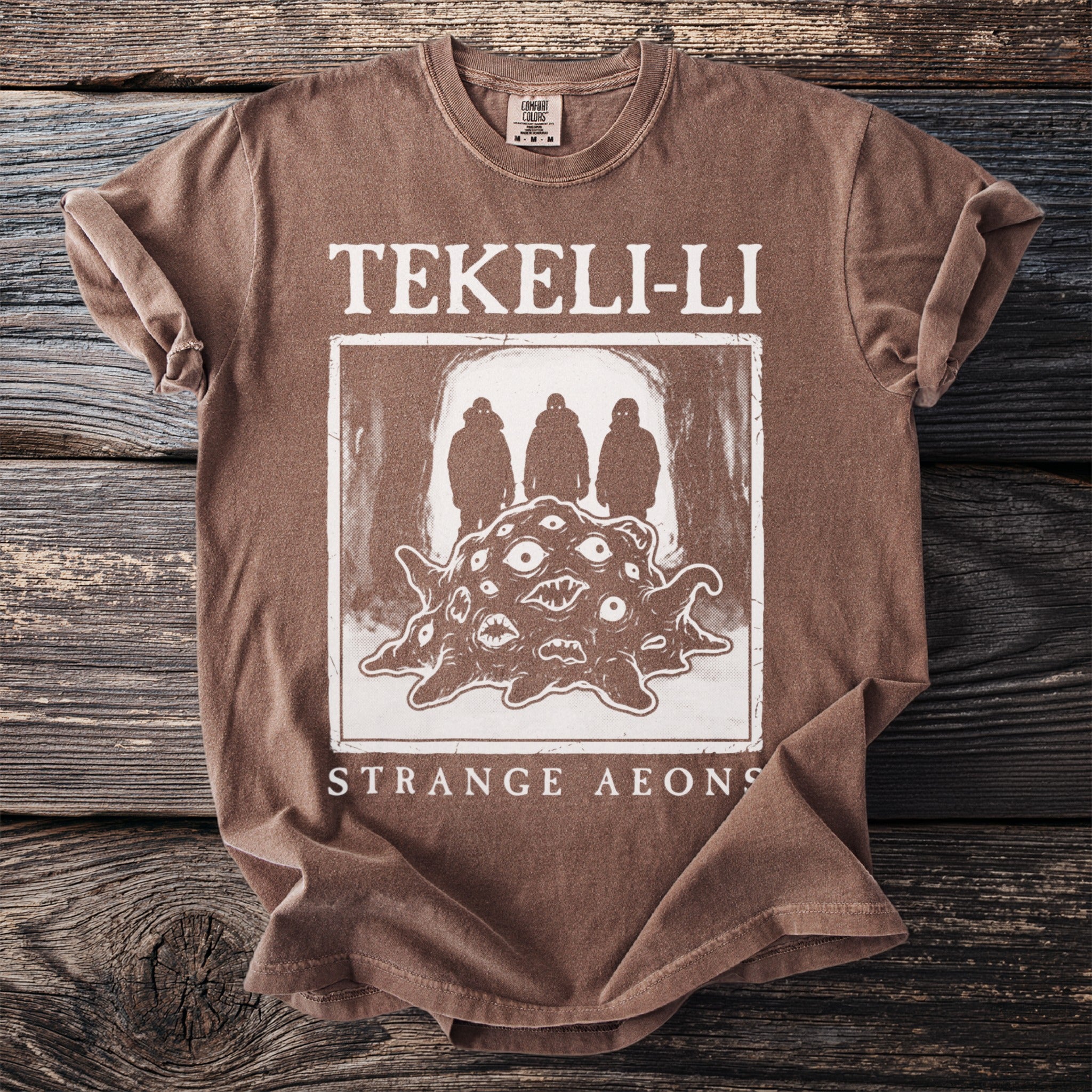 Brown t-shirt with "TEKELI-LI STRANGE AEONS" and monster graphic.