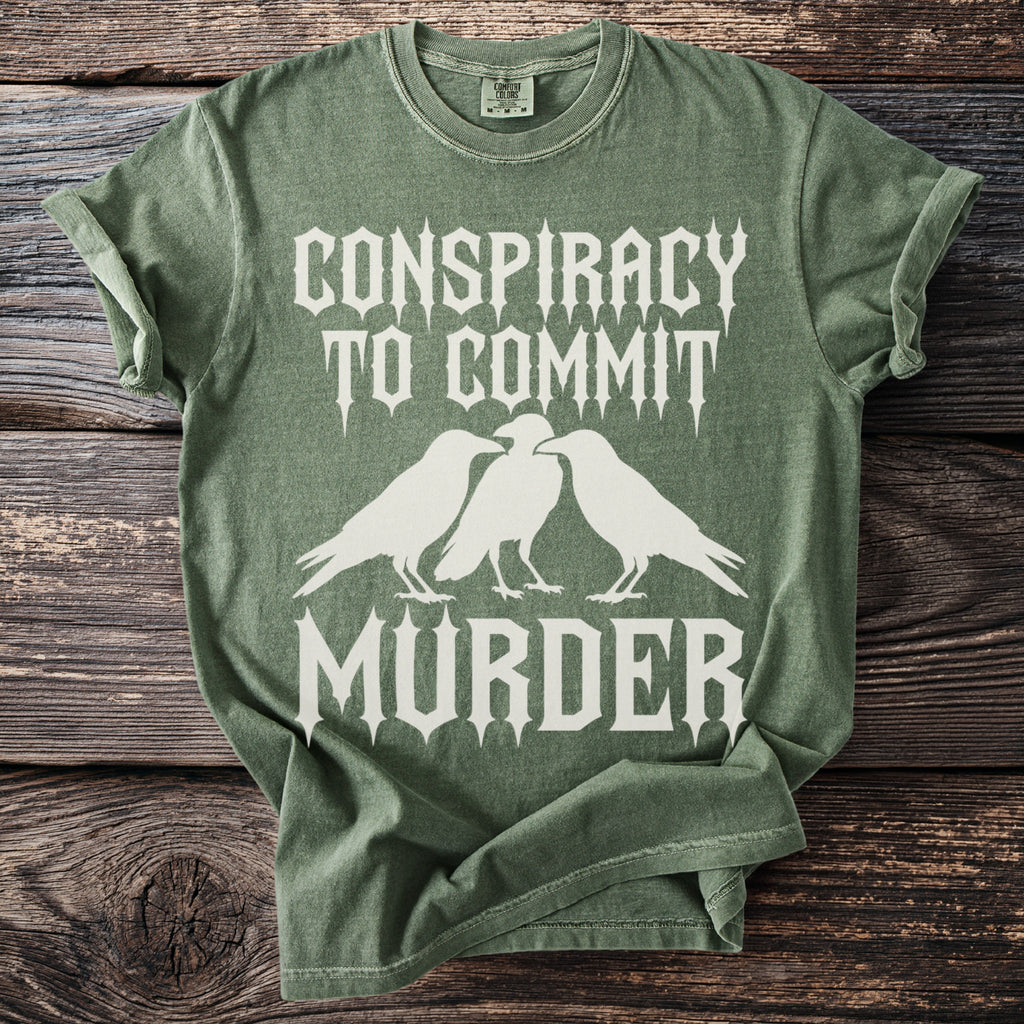 Green t-shirt with white text "Conspiracy to Commit Murder" and three crows.