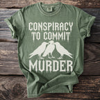 Green t-shirt with white text "Conspiracy to Commit Murder" and three crows.