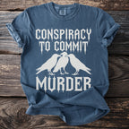 Blue t-shirt with white text "Conspiracy to commit murder" and three crows.