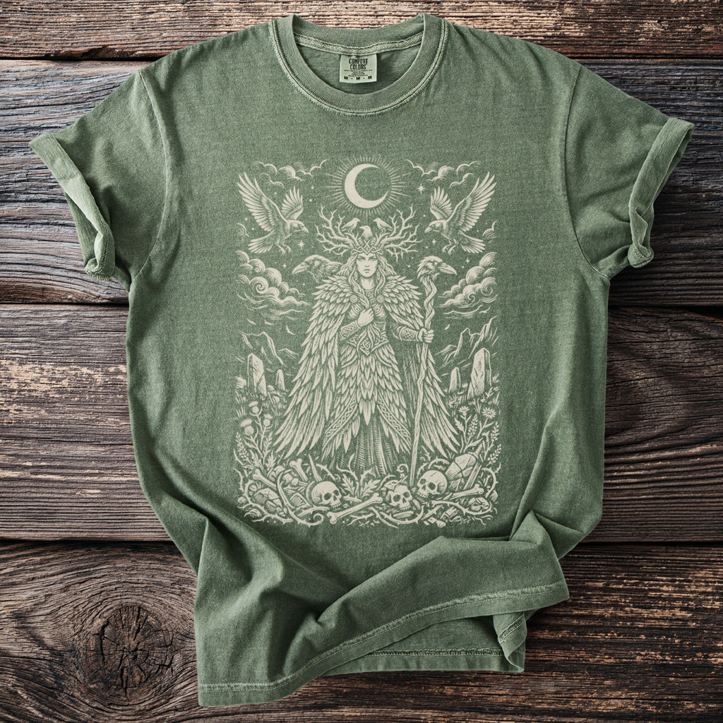 Sage green t-shirt with a detailed print of a mystical figure, birds, and skulls.