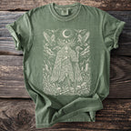 Sage green t-shirt with a detailed print of a mystical figure, birds, and skulls.
