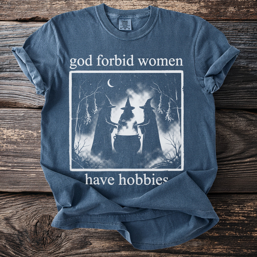 T-shirt with witches around a cauldron and text "god forbid women have hobbies."