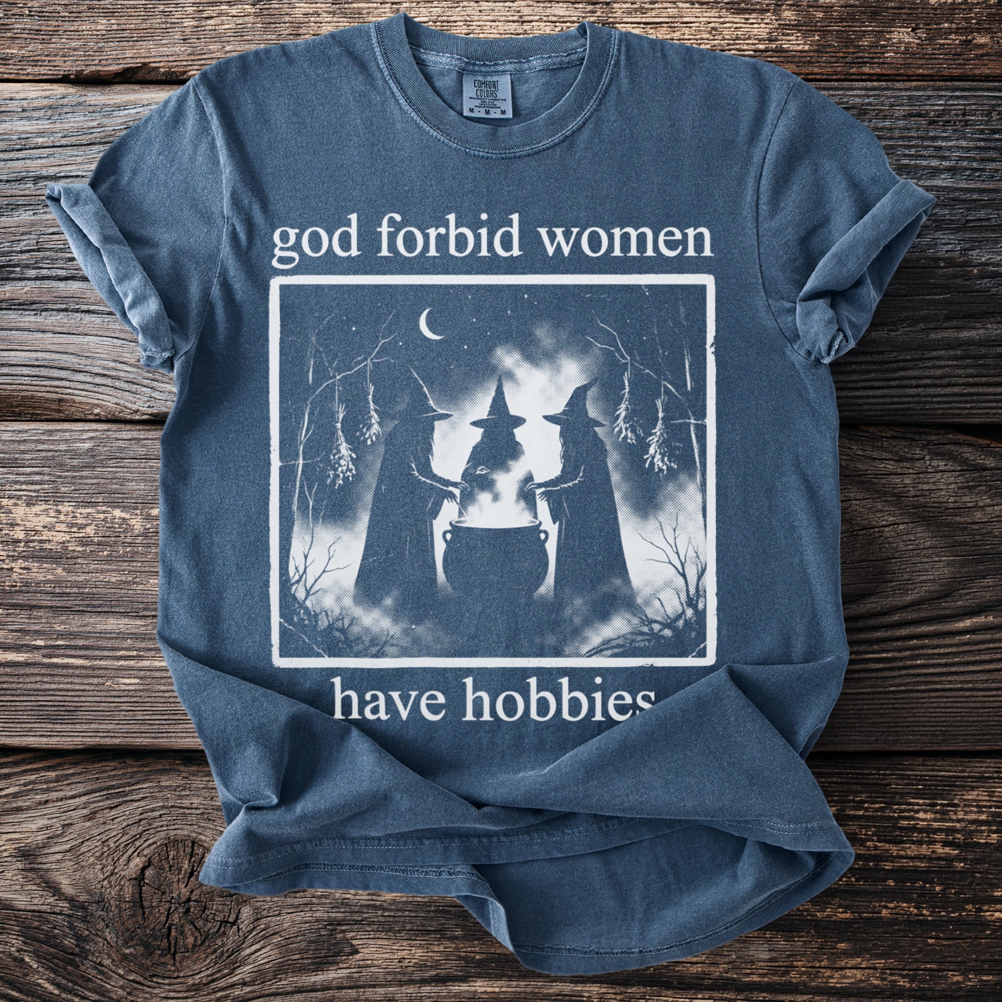 T-shirt with witches around a cauldron and text "god forbid women have hobbies."