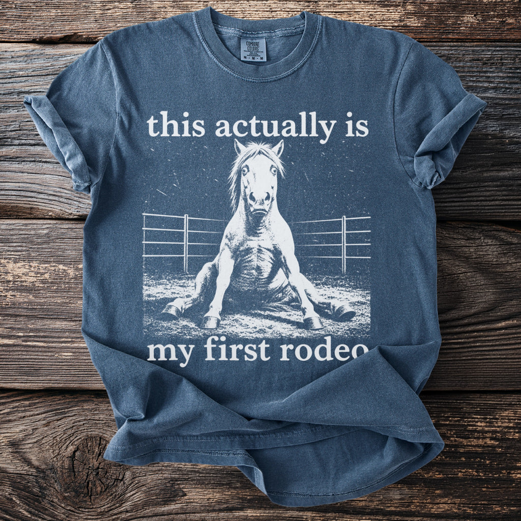 Blue t-shirt with text "this actually is my first rodeo" and a horse sitting down.