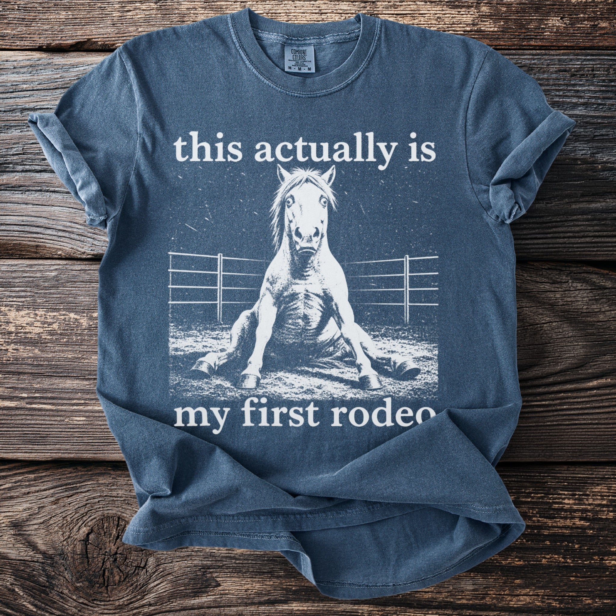 Blue t-shirt with text "this actually is my first rodeo" and a horse sitting down.