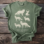 Green t-shirt with illustrations of six different fox species and text "The Fox Cabinet".