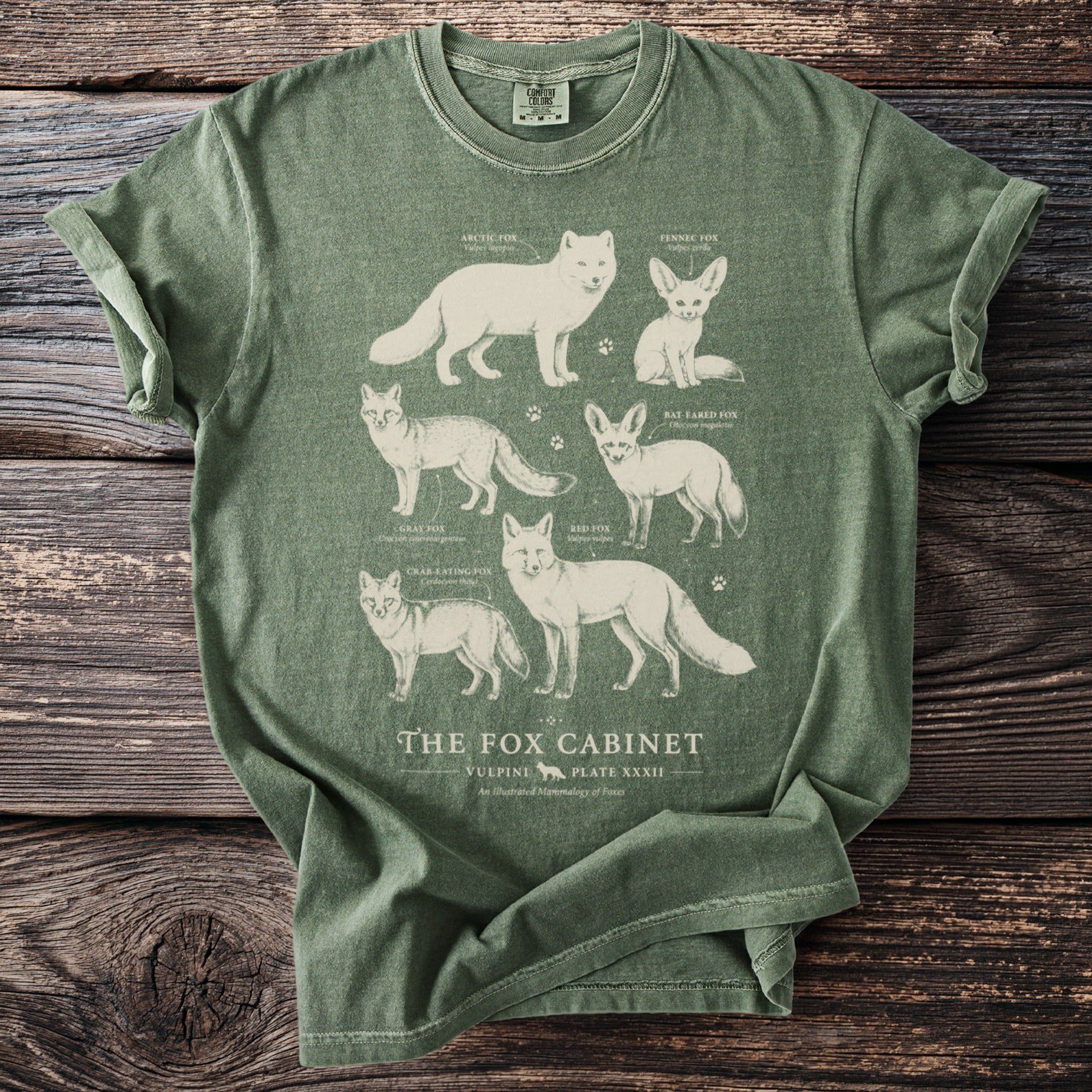 Green t-shirt with illustrations of six different fox species and text "The Fox Cabinet".