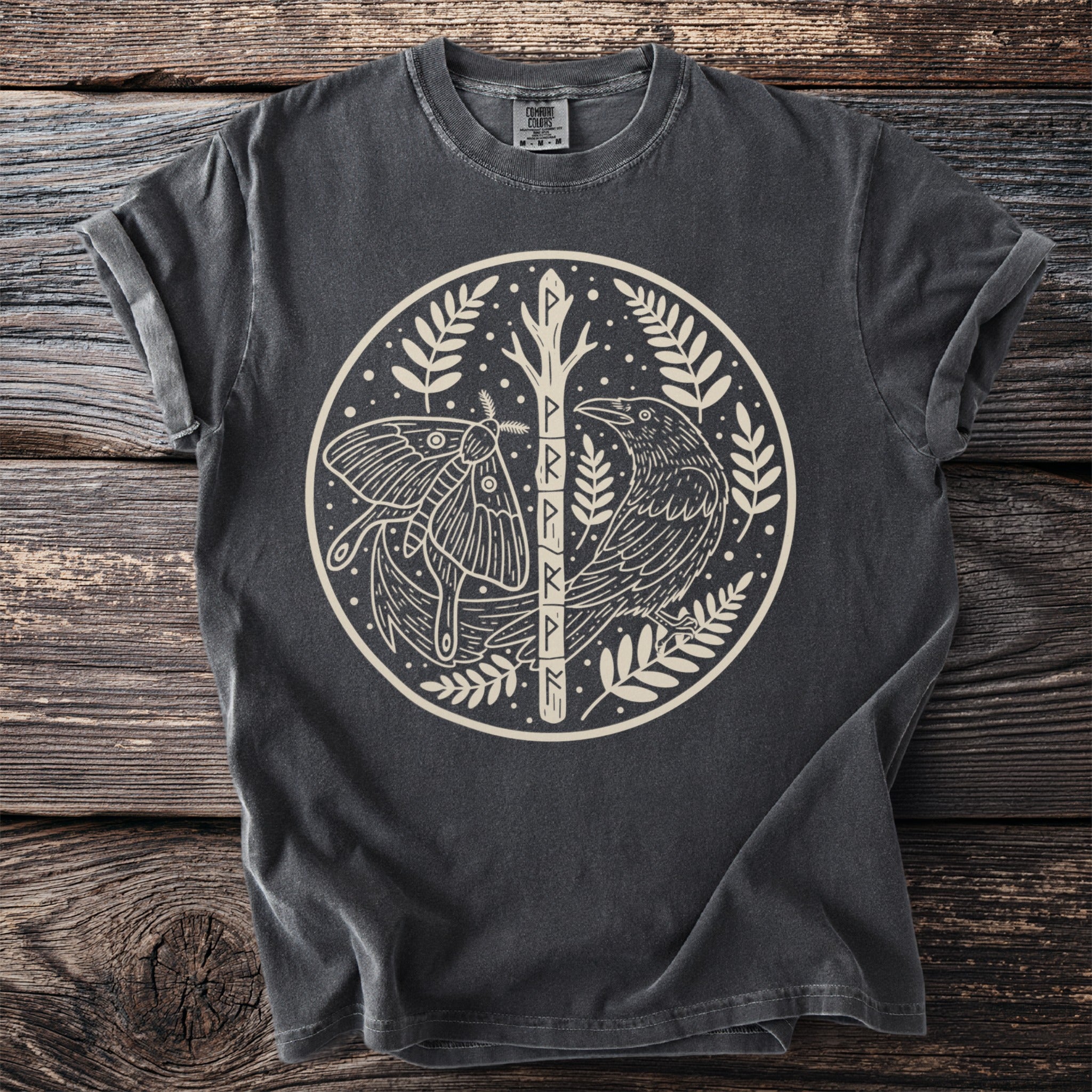 Dark grey t-shirt featuring a circular design with a moth, raven, and runes on a tree.