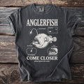 Dark gray t-shirt with Anglerfish graphic and text "COME CLOSER please ignore the teeth."