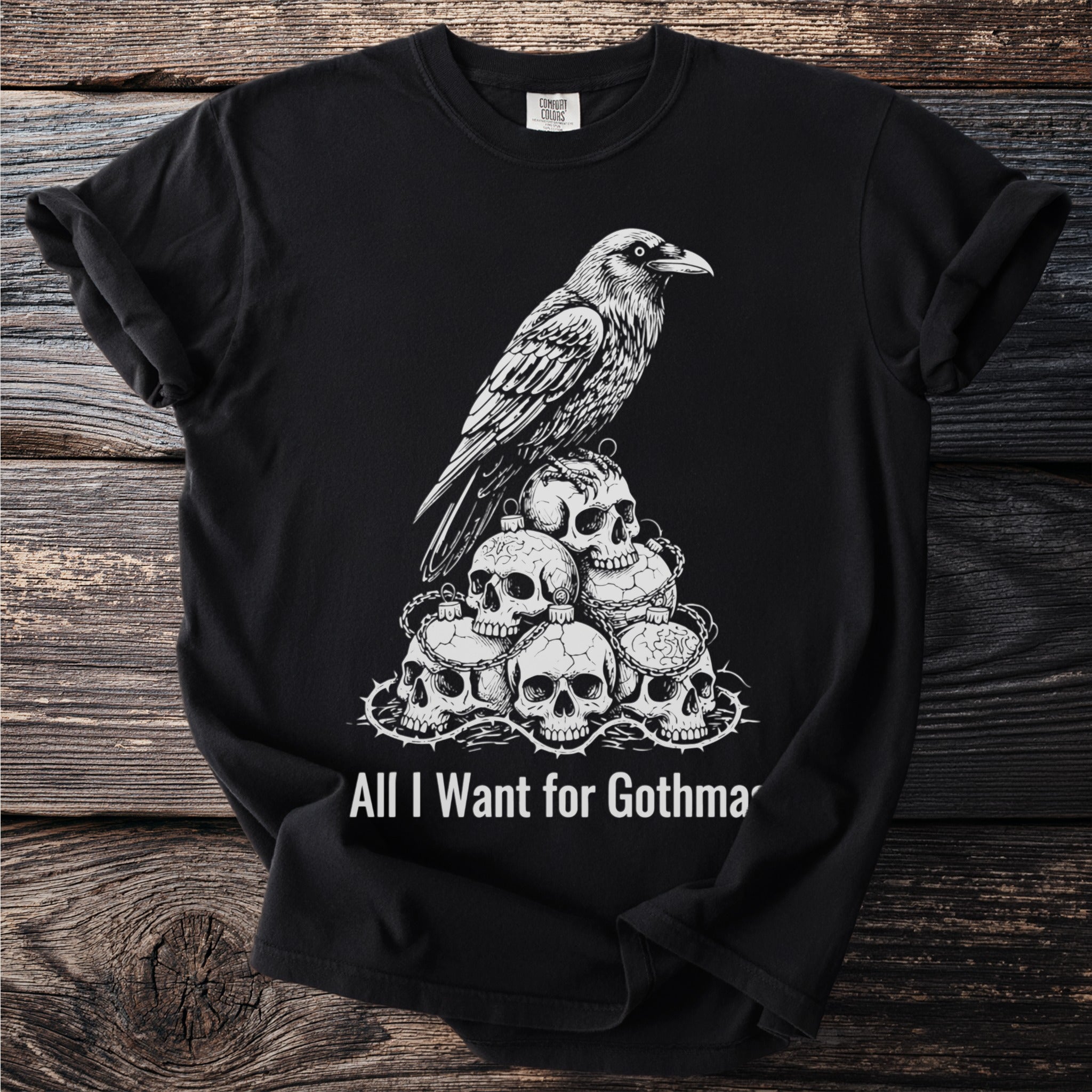 Black t-shirt with a raven perched on a pile of skulls and thorns, text reads "All I Want for Gothma".